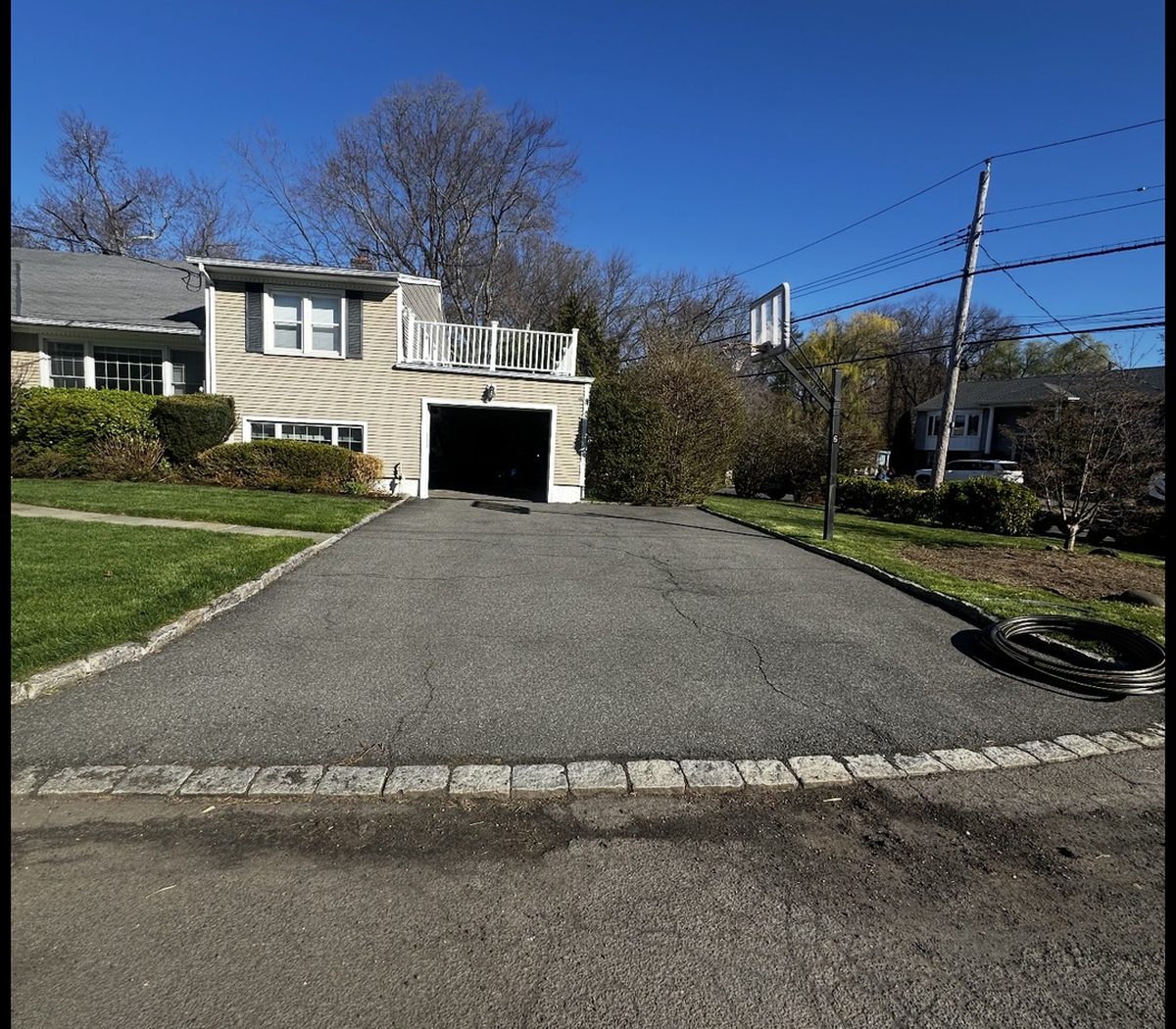 Residential asphalt driveway before the work: the surface is cracked across its full width and weathered to grey